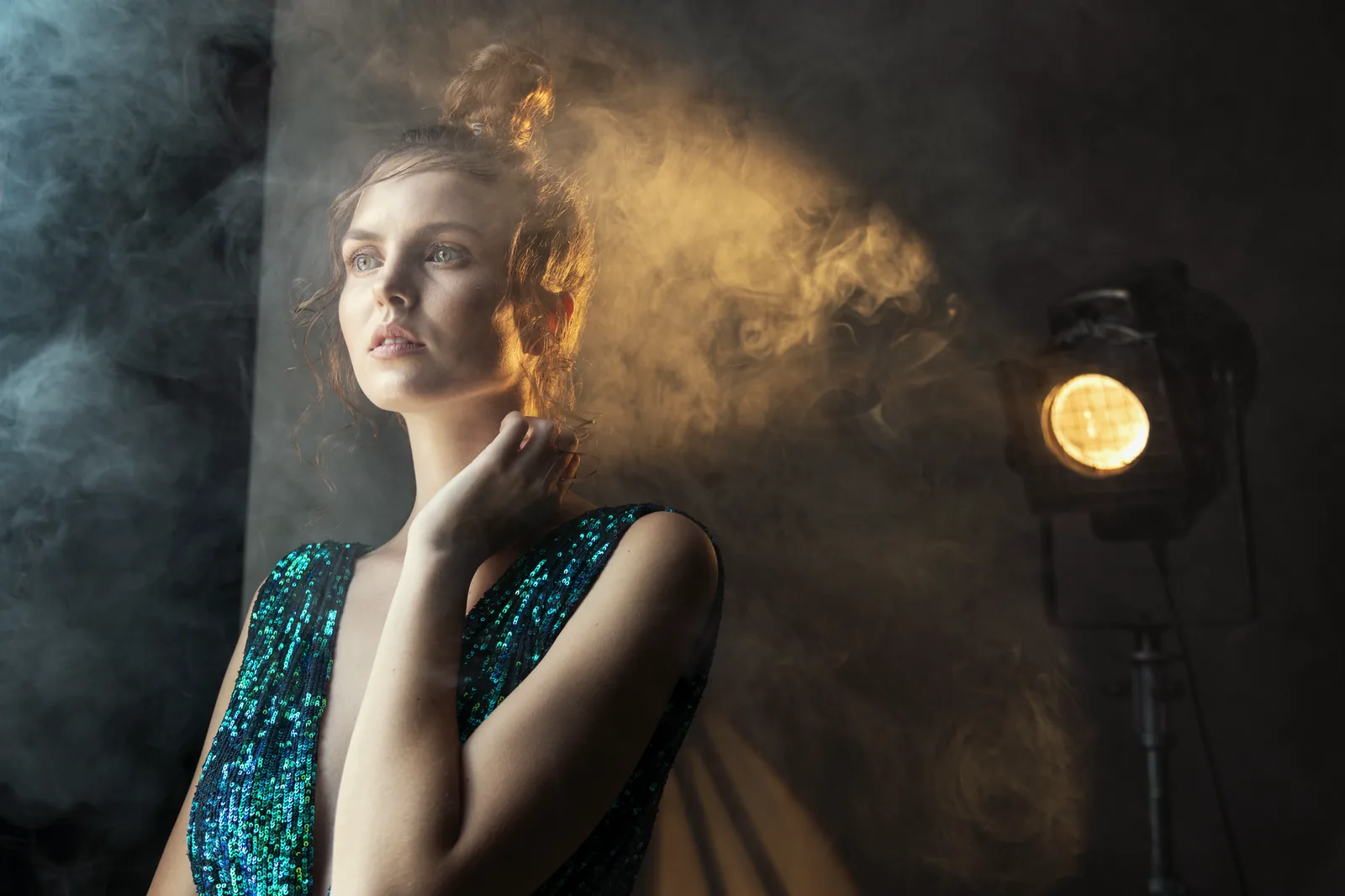 Portret kobiety w snopie światła reflektora, dym i kolory w tle
